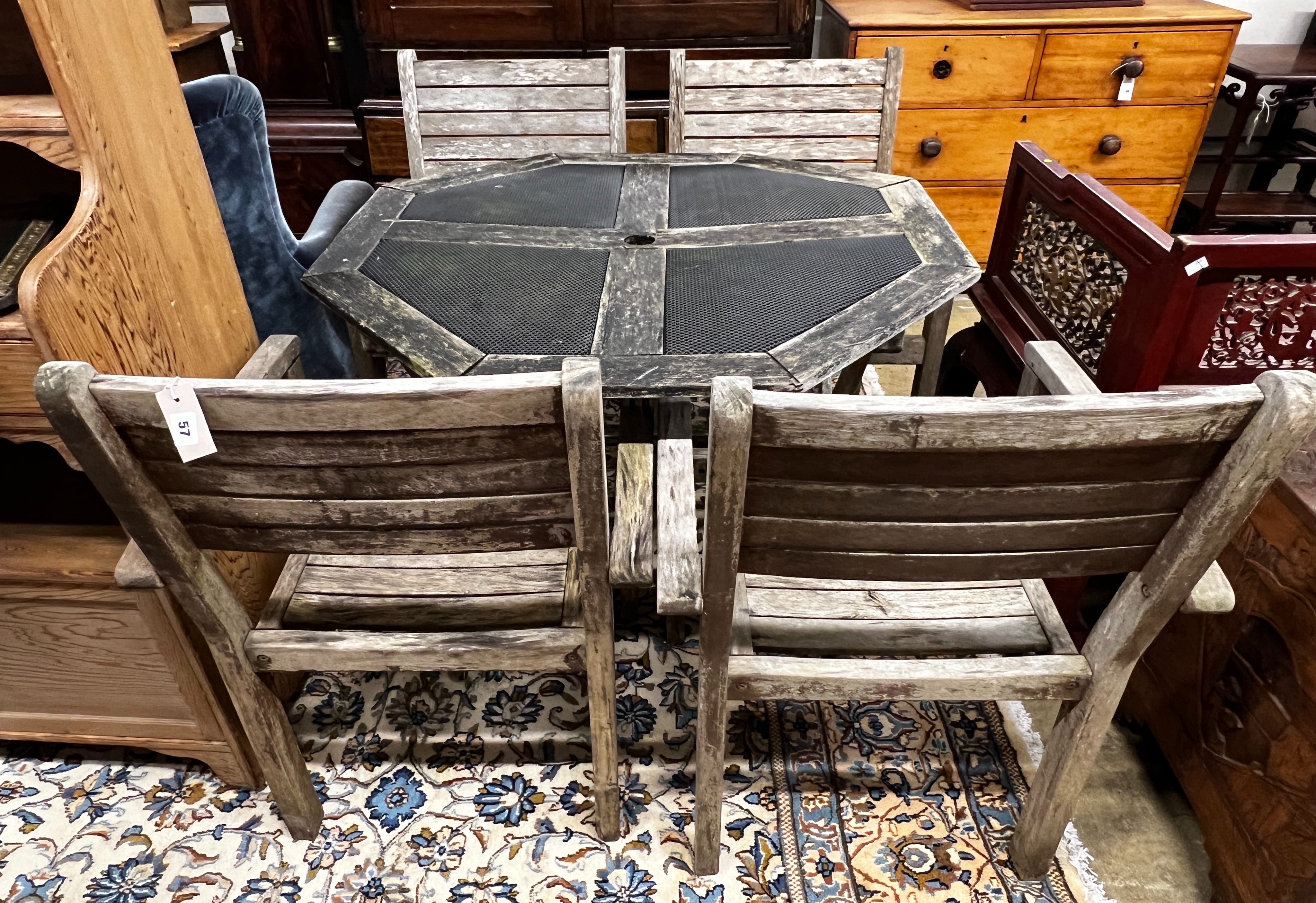 An octagonal weathered teak and mesh garden table, length 103cm, height 74cm together with four teak elbow chairs